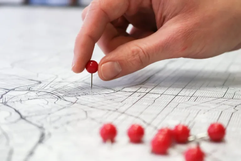 Hand placing a red location pin on a map representing local SEO and Google Map Pack rankings for real estate agents