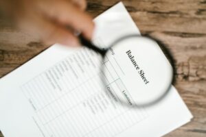 SEO audit services: magnifying glass examining financial document representing detailed website analysis for search ranking issues Rank Ray