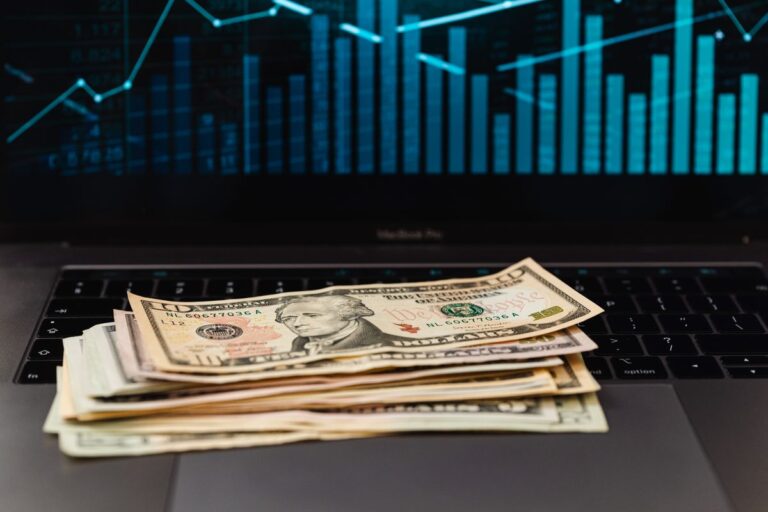 How much does SEO cost in 2026: dollar bills on laptop with financial growth graph representing SEO pricing and ROI for businesses Rank Ray